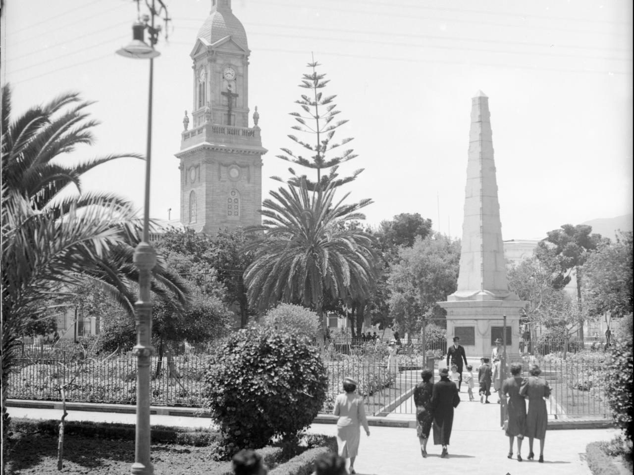 Plaza de Armas La Serena. Vista hacia Catedral, obelisco en medio de la plaza, al menos doce personas caminando